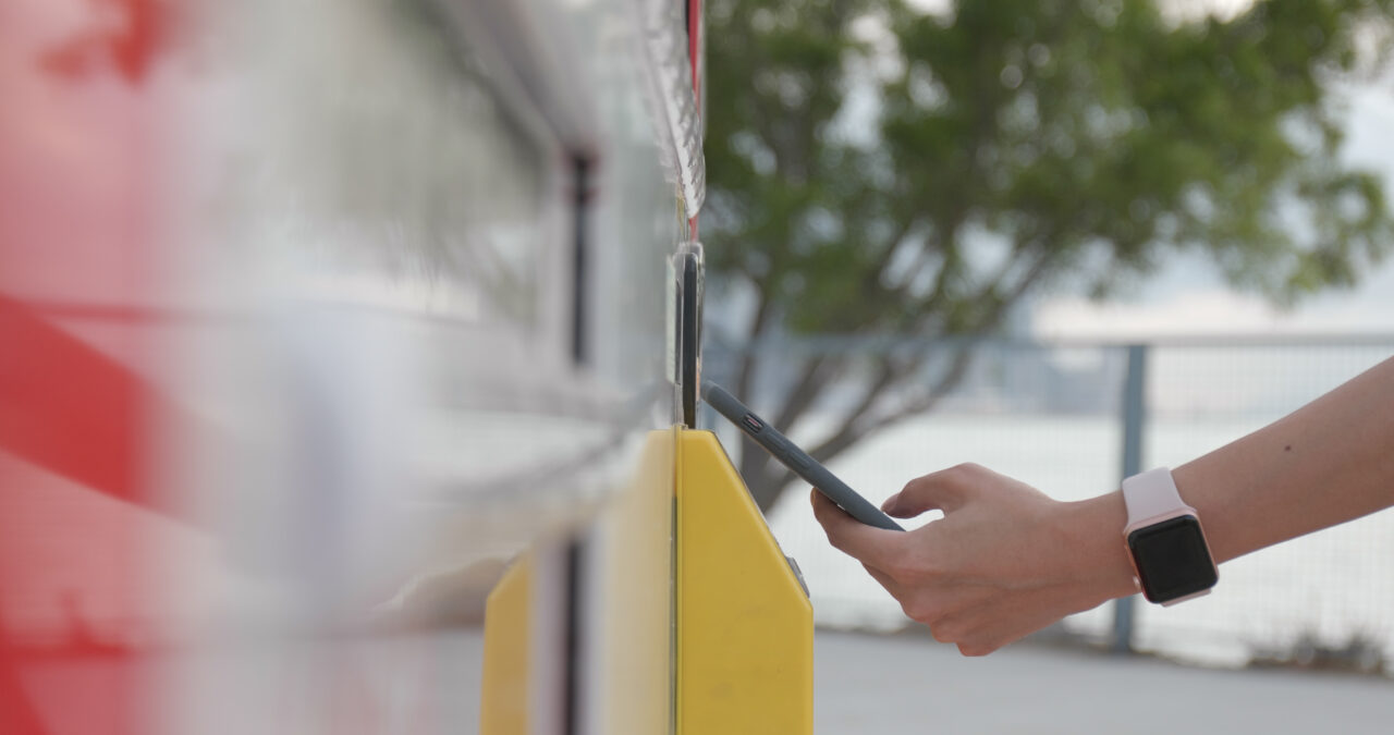 Woman using smart phone to pay at a vending machine