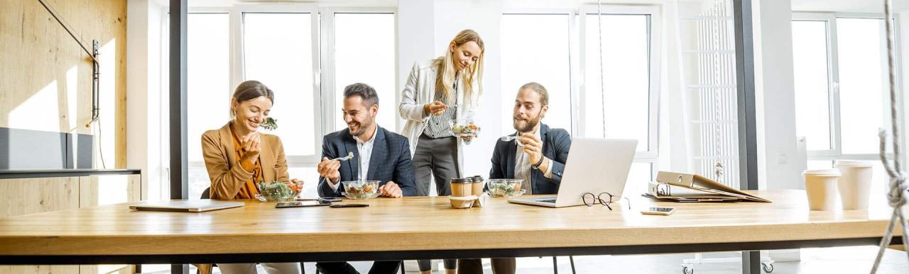 Colleagues eat healthy work lunch salad with coffee