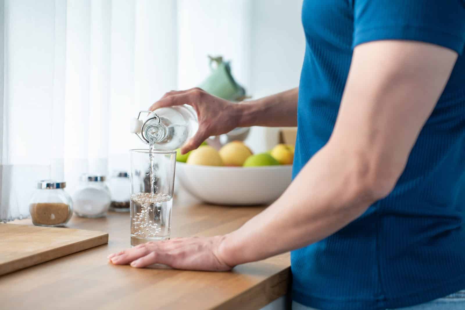 Close up hands of active strong man pouring clean water
