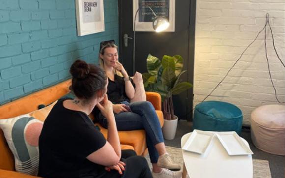 Two ladies chatting on an orange sofa
