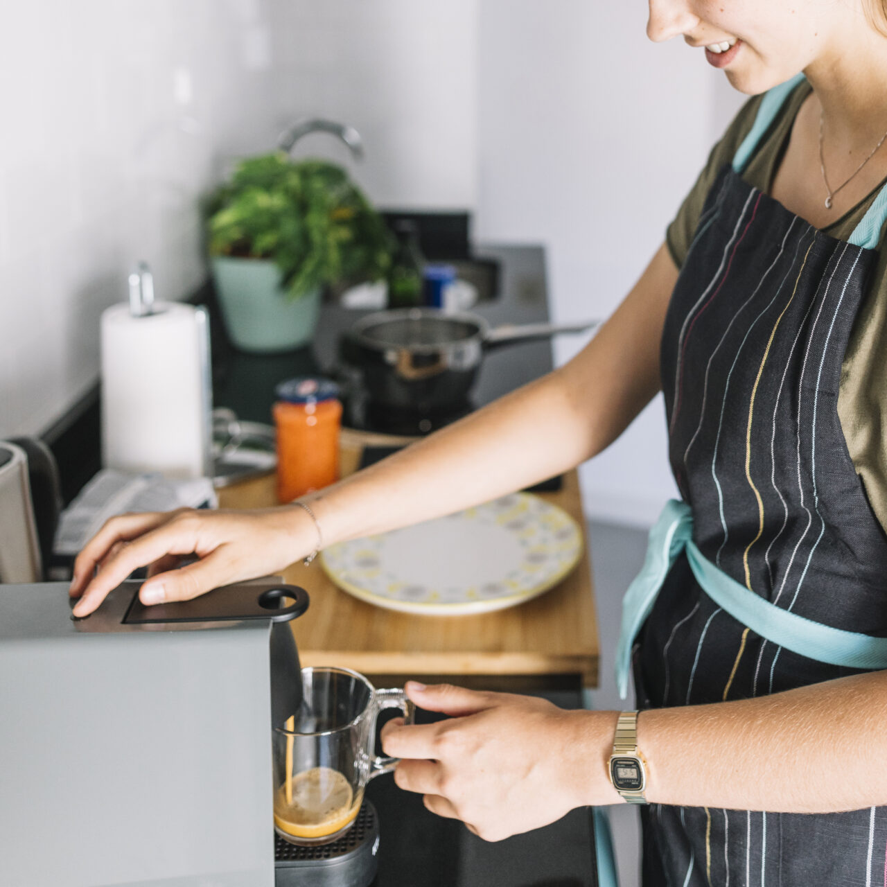 Smiling woman using an espresso coffee machine in a small space