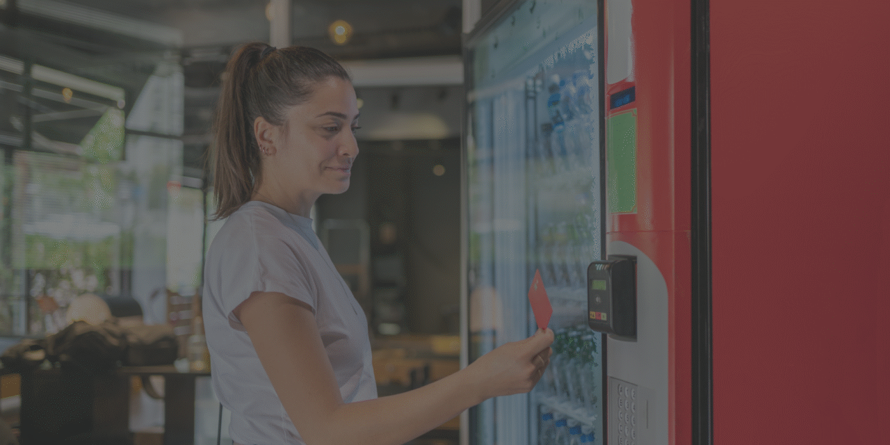 A woman uses a debit card to pay cashless at hyer office vending machine