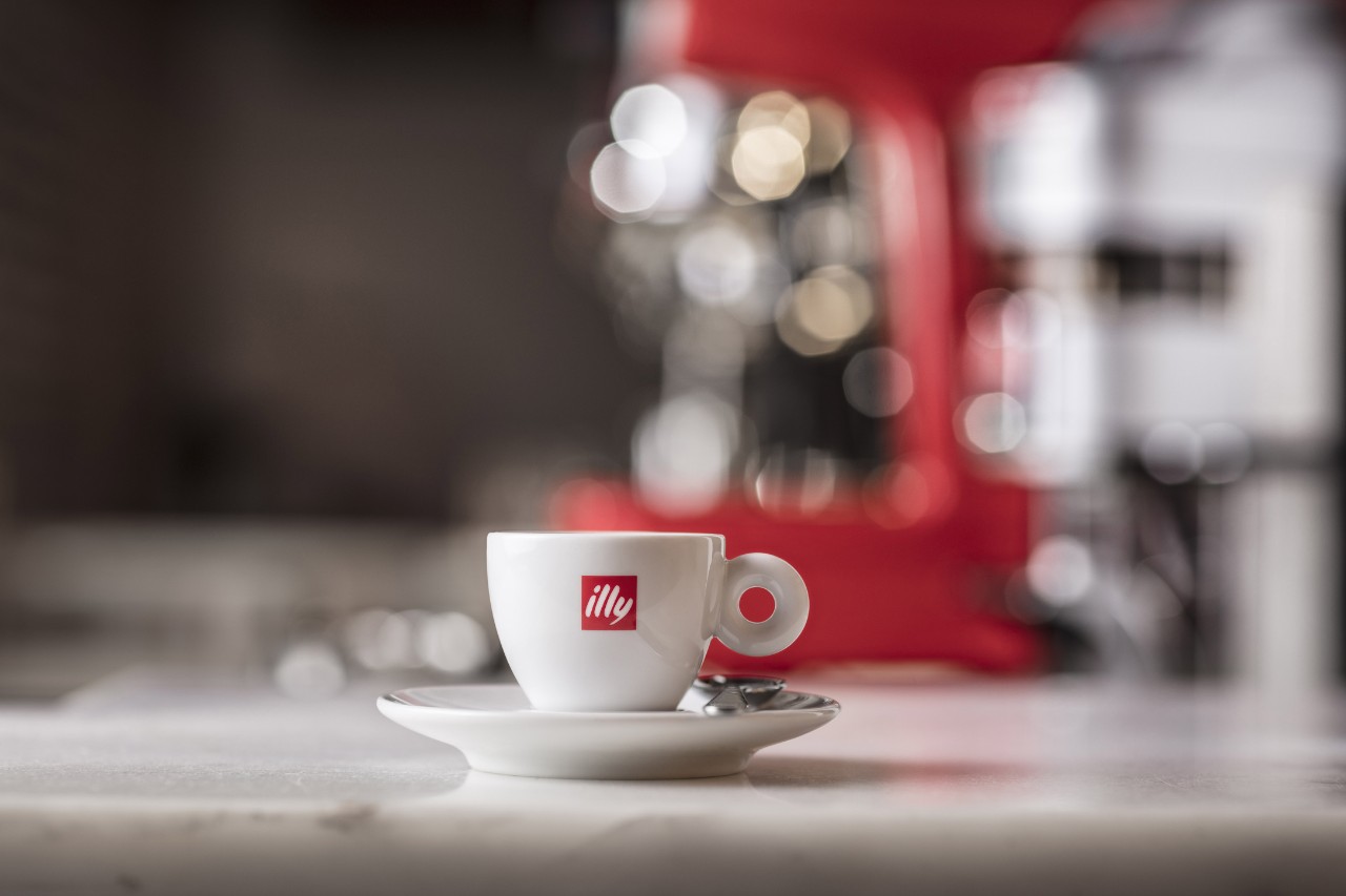 illy espresso cup in front of an illy coffee machine