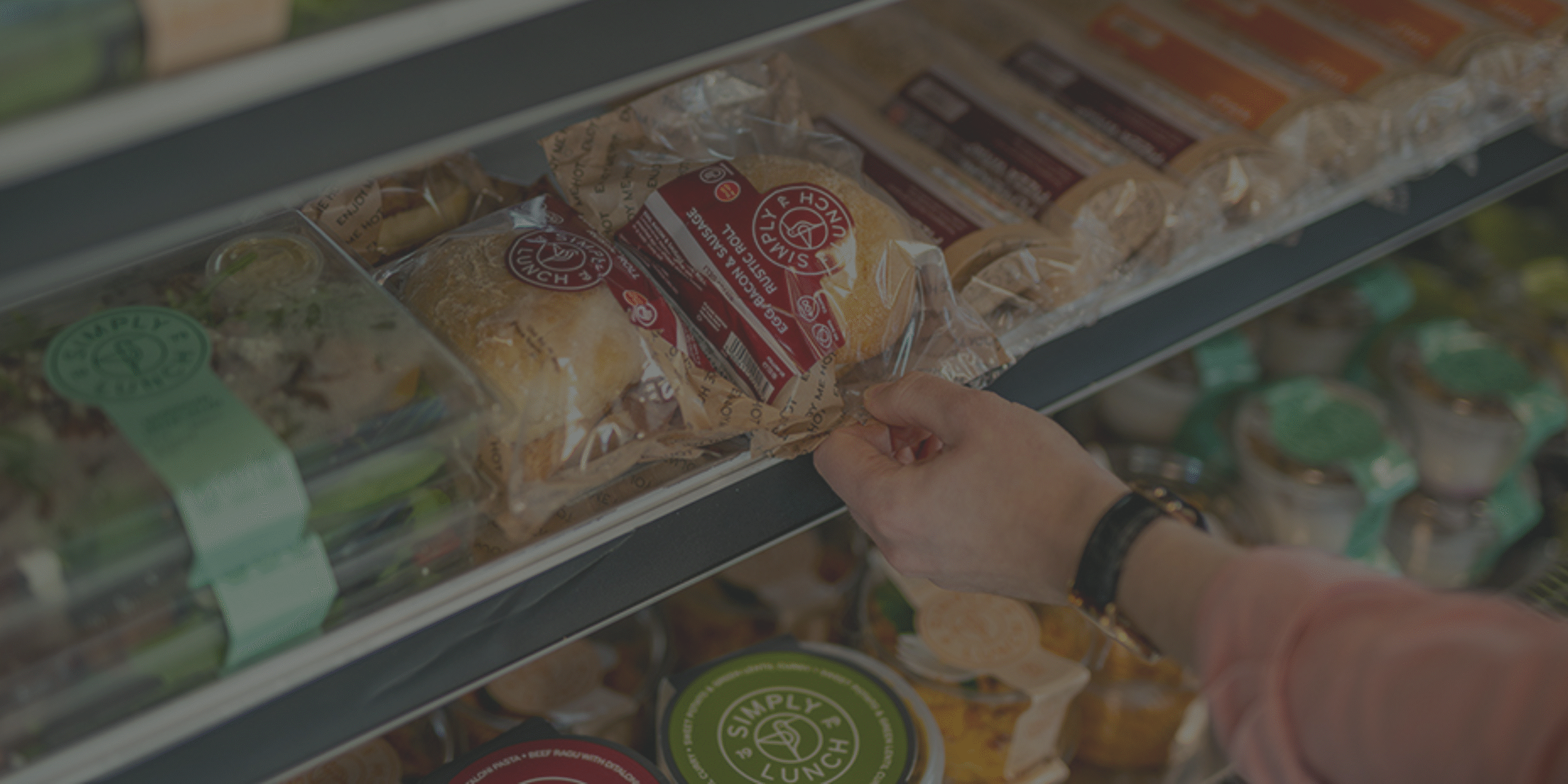 a worker selecting a premade sandwich from a micro market