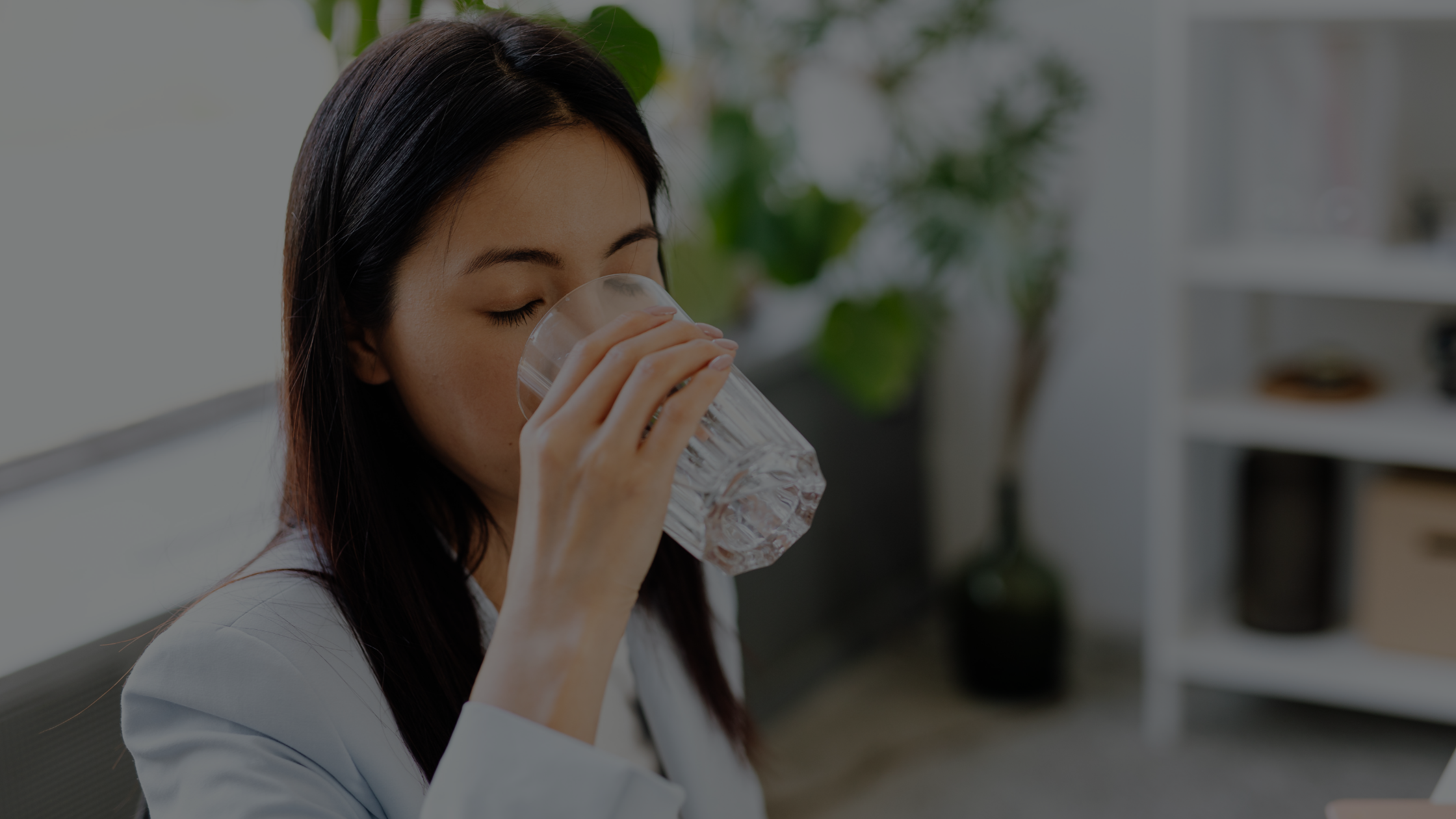 a smartly dressed woman drinks a glass of fresh filtered water